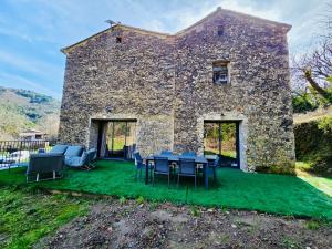 a stone house with blue tables and chairs on a lawn at Mas des châtaigniers in Le Vigan