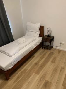 a bed with white sheets and a wooden floor at Apartments Adelheid in Wathlingen