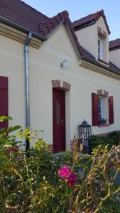 a white house with a red door and some bushes at Floralie parking privé navette vers Aéroport ou Gare Beauvais in Saint-Paul