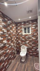 a bathroom with a toilet and a brick wall at شاليه لافندر ينبع in Yanbu Al Bahr