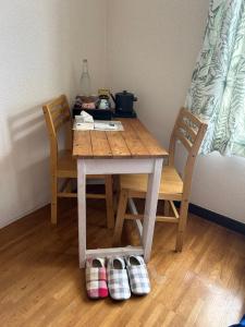 a wooden table with two chairs and shoes on the floor at なかじま宿 in Uenomachi