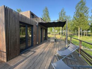 a wooden deck with chairs and a house at Au fil de l’eau, gîte nature in Abbécourt