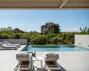 a swimming pool with chairs and a table and a swimming pool at Hesperian Luxury Villas with Private Heated Pools in Chania