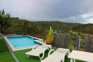 a swimming pool with two chairs and a table at Casa do Cabeço in Proença-a-Nova