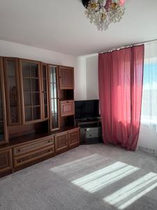 a living room with a red curtain and a television at NV Apartments in Volodymyr-Volynskyi