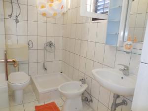 a white bathroom with a toilet and a sink at Apartments Veni Up in Starigrad-Paklenica