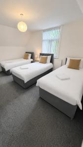 a room with three beds and a window at Apex Rooms Salford - Free Parking in Manchester