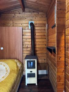 a room with a stove and a bed in a cabin at Florea Cottage in Ulcinj