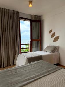 two beds in a hotel room with a window at Pousada Mahalo Preá Beach in Prea