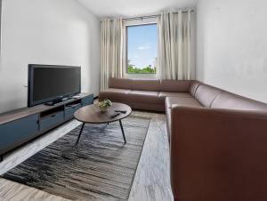 a living room with a couch and a tv at Spacious Pereybere 3BR Apartment in Grand-Baie