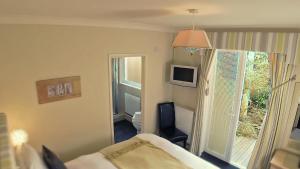 1 dormitorio con cama, ventana y TV en Lamorna Lodge, en St Ives