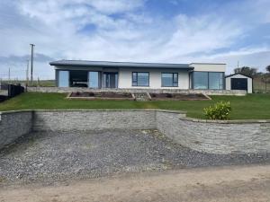 a house with a stone retaining wall in front of it at Tigh an Trá in Bantry
