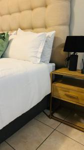 a bed with white sheets and a nightstand with a lamp at DL Apartments in Palatswe