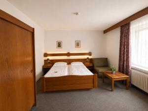 a bedroom with a bed and a chair at Hotel Wildpferd Dülmen in Dülmen