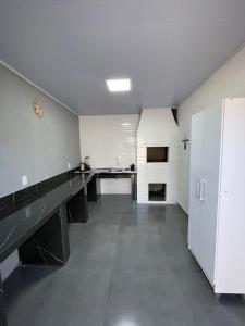 a large kitchen with black counters and white walls at Pousada aconchego in Imbituba