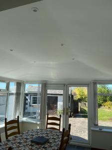 a dining room with a table and some windows at Rose Cottage Moira in Moira