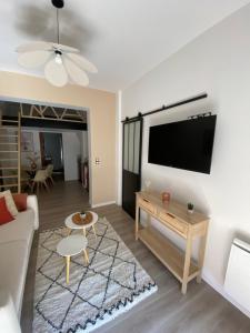 a living room with a couch and a tv on a wall at La Cabane Perché in Ault