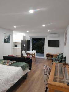 a room with a bed and a table and a kitchen at The Hideaway in Raumati Beach