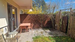 a patio with a table and chairs and a fence at Les Hautains in Saint-Genis-Pouilly