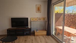 a living room with a flat screen tv and a table at Les Hautains in Saint-Genis-Pouilly