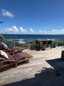 a patio with chairs and a table and the ocean at Villa Dérimbeault in Oyster Pond