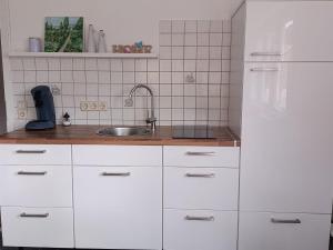 a kitchen with white cabinets and a sink at Gemütliche Ferienwohnung in Philippsburg