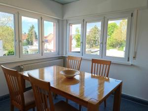 a dining room with a wooden table and four windows at Gemütliche Ferienwohnung in Philippsburg