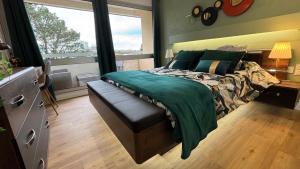 a bedroom with a bed with a green comforter and a window at Bénodet appartement 100m de la plage thalasso 2chambres parking privé internet avec box in Bénodet