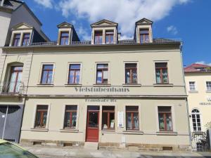 a large white building with a red door at Vielstubenhaus - FeWo August in Pirna
