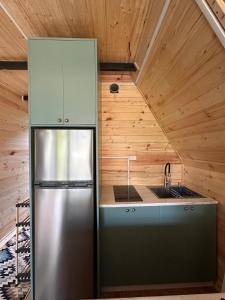 a kitchen with a stainless steel refrigerator and wooden walls at Cottage Green Horizon Buknari in Buknari +28 photos