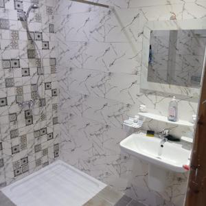 a white bathroom with a sink and a mirror at Résidence Rahma in Hammam Chott