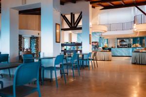 a restaurant with blue chairs and tables and a bar at Villaggio Torre Ruffa Robinson in Capo Vaticano