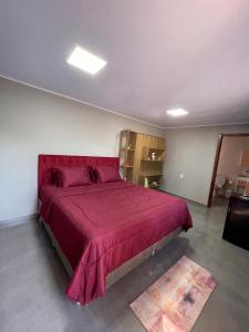 a bedroom with a large bed with a red blanket at suíte perto da praia in Imbituba