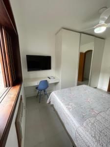 a bedroom with a bed and a desk with a television at Quarto da Fran - perto da UFF in Niterói