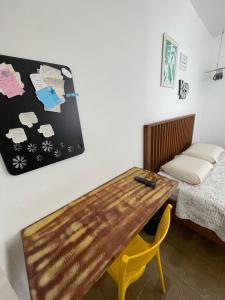 a room with a wooden table and a bed at Suíte da Fran - Perto da UFF in Niterói