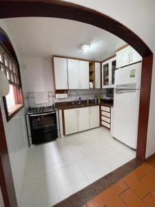 a kitchen with white cabinets and a white refrigerator at Suíte da Fran - Perto da UFF in Niterói