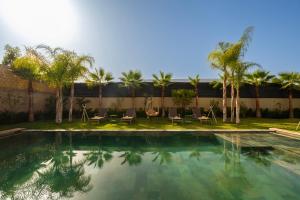 a swimming pool with chairs and palm trees at Luxurious Marrakech Villa Pool, Hammam,Cinema in Marrakesh