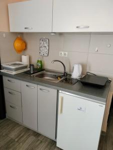 a kitchen with white cabinets and a sink at Gagin San -apartman na plaži in Veliko Gradište