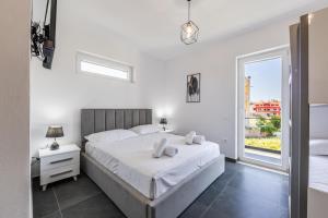 a white bedroom with a large bed and a window at Crystal Beach Rooms by PS in Durrës
