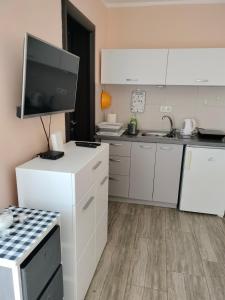 a kitchen with white cabinets and a flat screen tv at Gagin San -apartman na plaži in Veliko Gradište +10 photos
