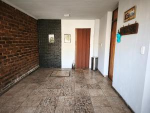 a hallway with a brick wall and a red door at Pausa viajera in Las Heras