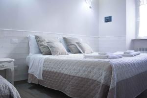 Dormitorio blanco con cama con sábanas y almohadas blancas en Clara Domus en Roma