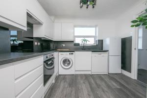 a kitchen with white cabinets and a washer and dryer at Seaview in Clacton-on-Sea +19 photos
