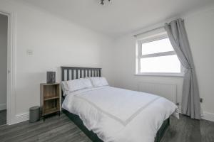 a white bedroom with a bed and a window at Seaview in Clacton-on-Sea