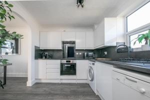 a kitchen with white cabinets and a sink at Seaview in Clacton-on-Sea