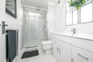 a white bathroom with a shower and a toilet and a sink at Seaview in Clacton-on-Sea