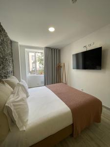 a bedroom with a large bed and a flat screen tv at Esmeralda Holidays Apartments in Funchal