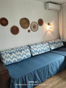 a blue couch in a room with plates on the wall at Estudio DUNA BLANCA in Matalascañas
