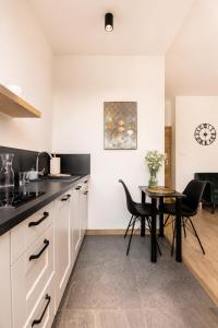a kitchen with white cabinets and a table with chairs at PiotrApartments - Central Warsaw Wilcza - Luxury Apartment - Prime Location in Warsaw
