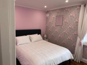 a bedroom with a white bed with pink floral wallpaper at Knockeven Hidden Gem in Waterford
